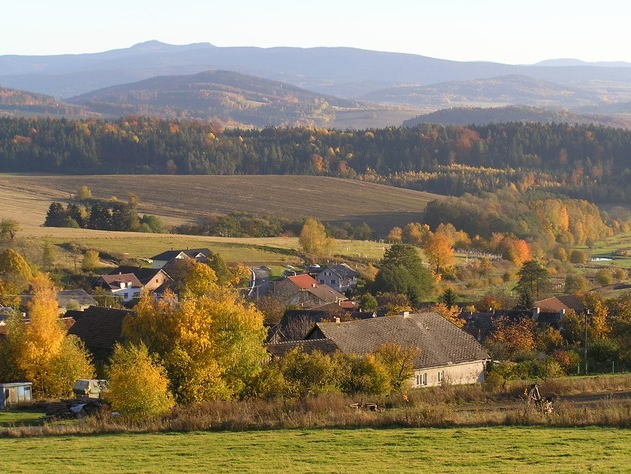 Obec v údolí obklopeném zalesněnými vrchy